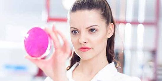 Microbiologist holding pink petri dish