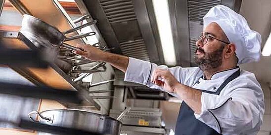 chef in kitchen wearing uniform, apron and hat