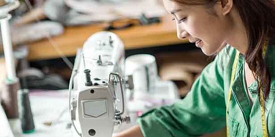 Asian textile worker in green shirt at a sewing machine