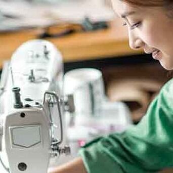 Asian textile worker in green shirt at a sewing machine