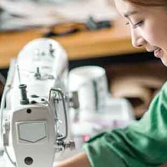 Asian textile worker in green shirt at a sewing machine