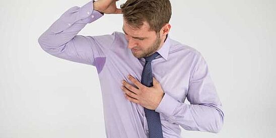 Man looking at sweat on his shirt