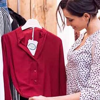 Shopper near rack of shirts, looking at a label