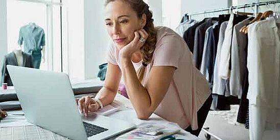 Female working on laptop in apparel design studio