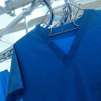 Blue scrubs conveyed through industrial laundry