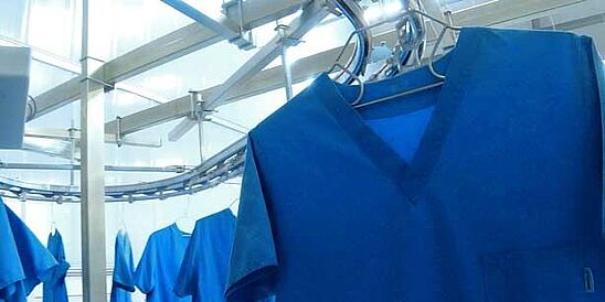 Blue scrubs conveyed through industrial laundry