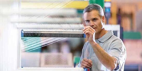 Male worker adjusting a textile machine