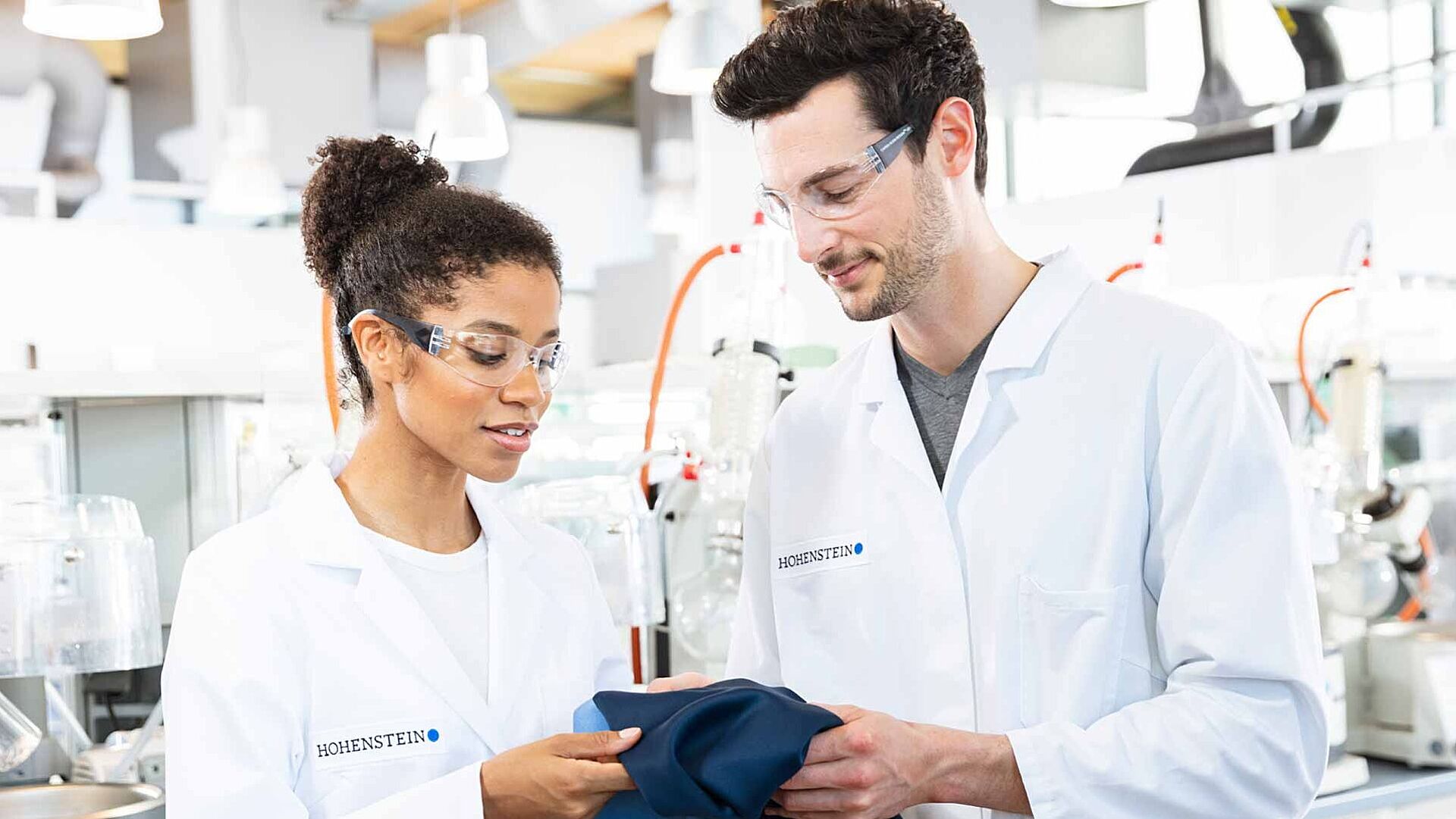 Two Hohenstein lab technicians analyzing a blue textile