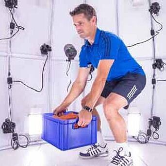 Man wearing athletic clothes and footwear, lifting crate in 4D scanner at Hohenstein