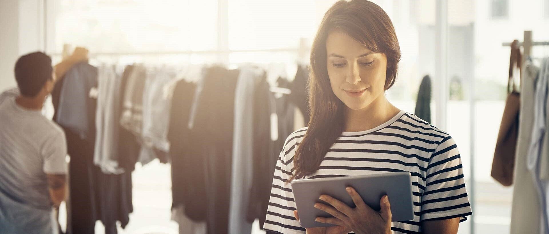 Apparel designer in striped shirt using a tablet