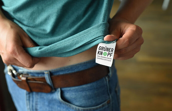 Person in green t-shirt showing green button sew-in label