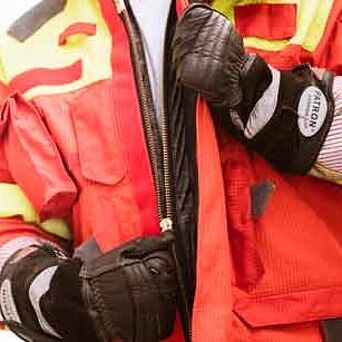 Firefighter wearing protective gloves and unzipping jacket