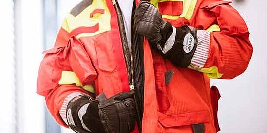 Firefighter wearing protective gloves and unzipping jacket