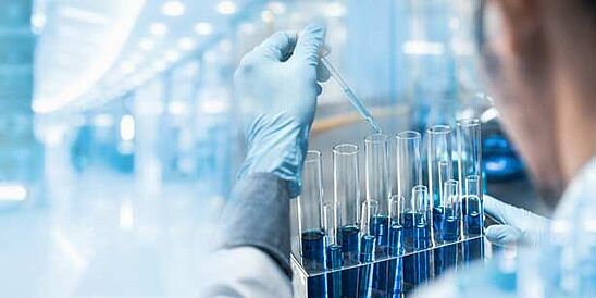 Chemist with vials of blue chemicals in Hohenstein chemical testing lab