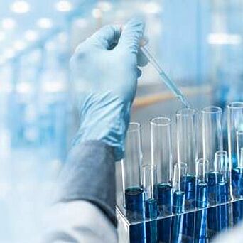 Chemist with vials of blue chemicals in Hohenstein chemical testing lab