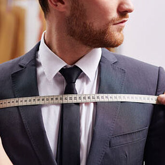 Clothing engineer measuring fit of a man's suit