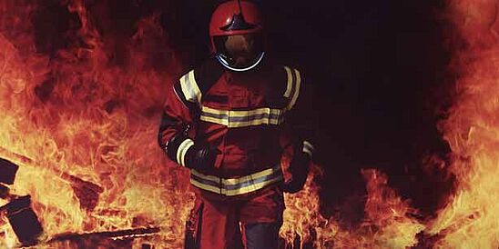 Fire fighter wearing helmet and running out of a fire.