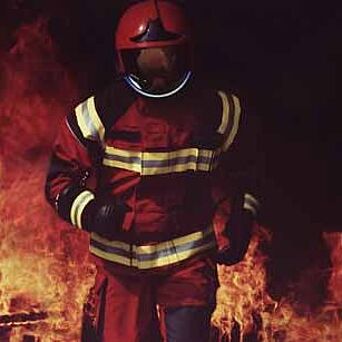 Fire fighter wearing helmet and running out of a fire.