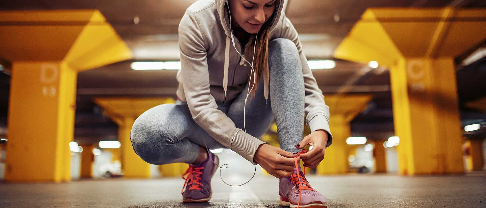 Woman leaning down to tie athletic shoe