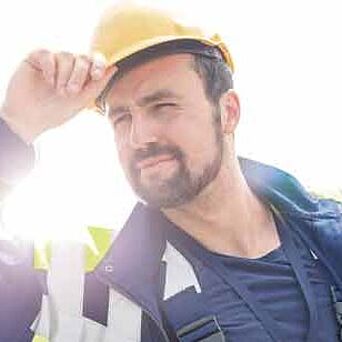 Worker in hardhat and protective gear on sunny day