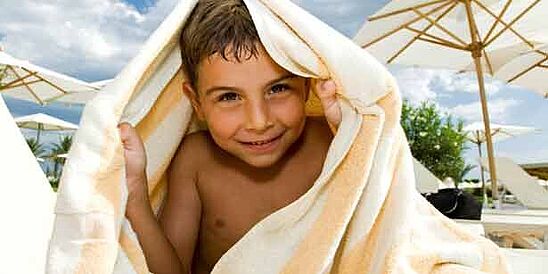 Boy shielding sun with towel