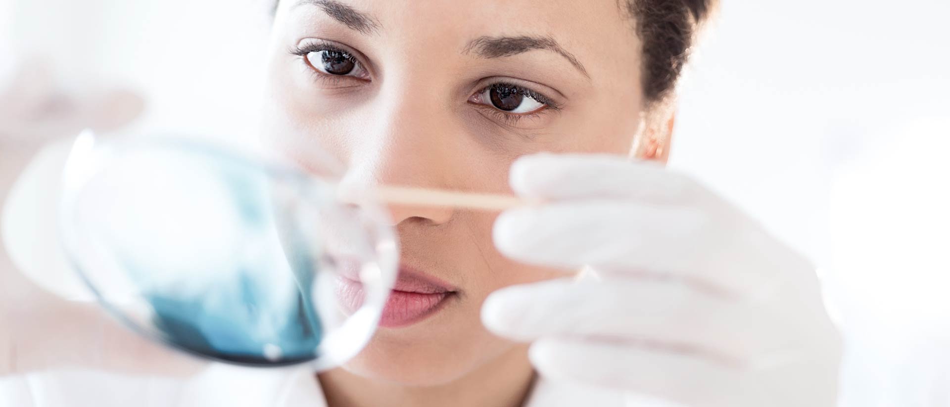 chemist holding dish of blue chemicals in Hohenstein testing lab