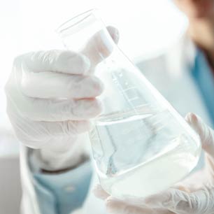 Textile engineer holding a beaker with chemicals