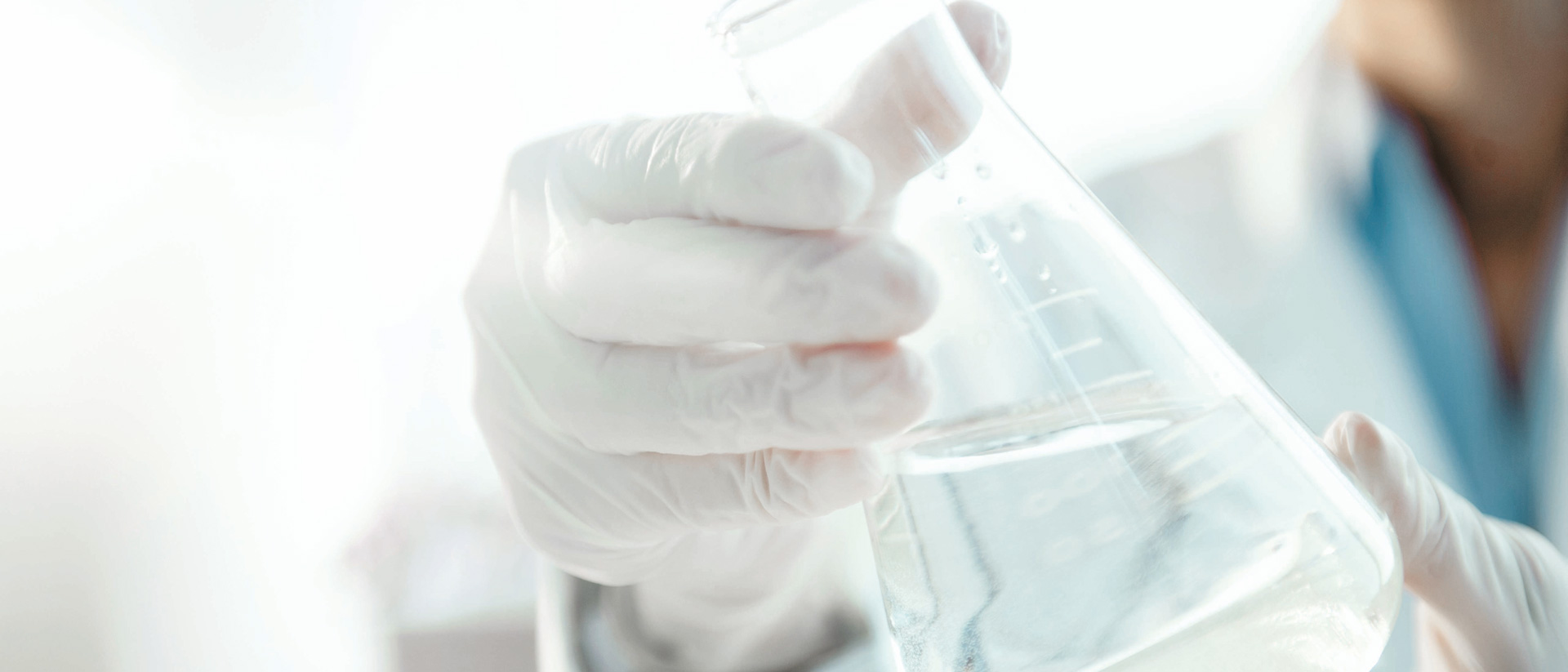 Chemist holding beaker of textile chemicals