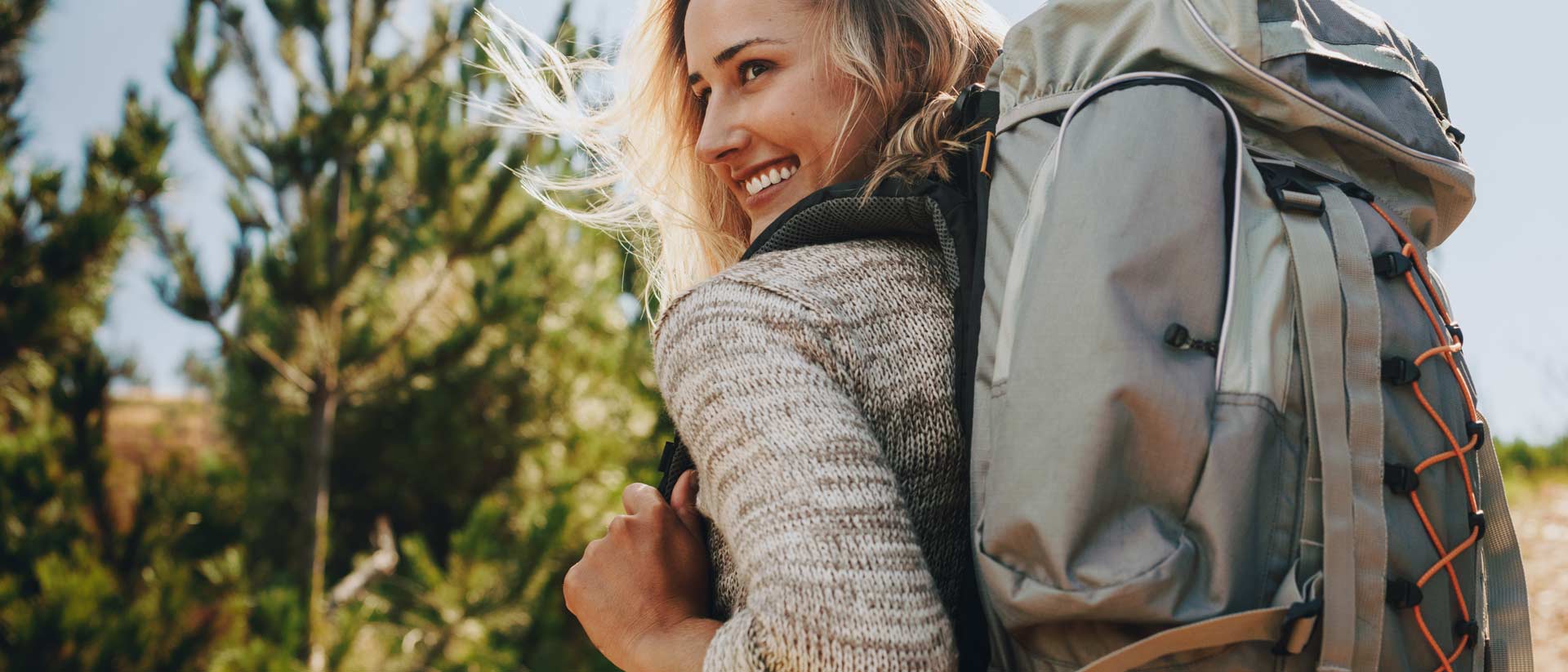 Woman wearing hat and backpack hiking outdoors