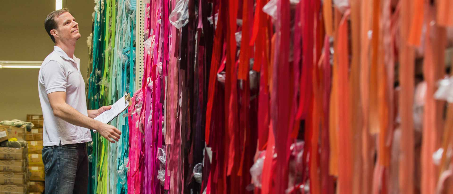 Textile worker checking certified fabric samples in many colors