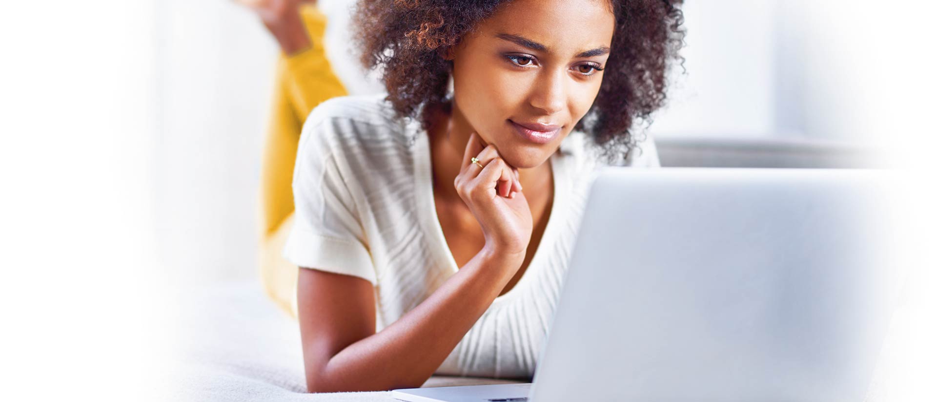 Woman with white shirt and yellow pants looking at computer