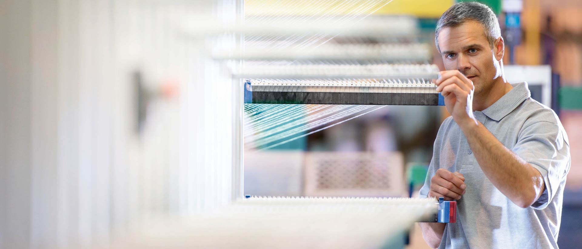 Worker adjusting a textile weaving machine