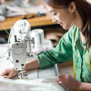 Asian textile worker in green shirt at a sewing machine