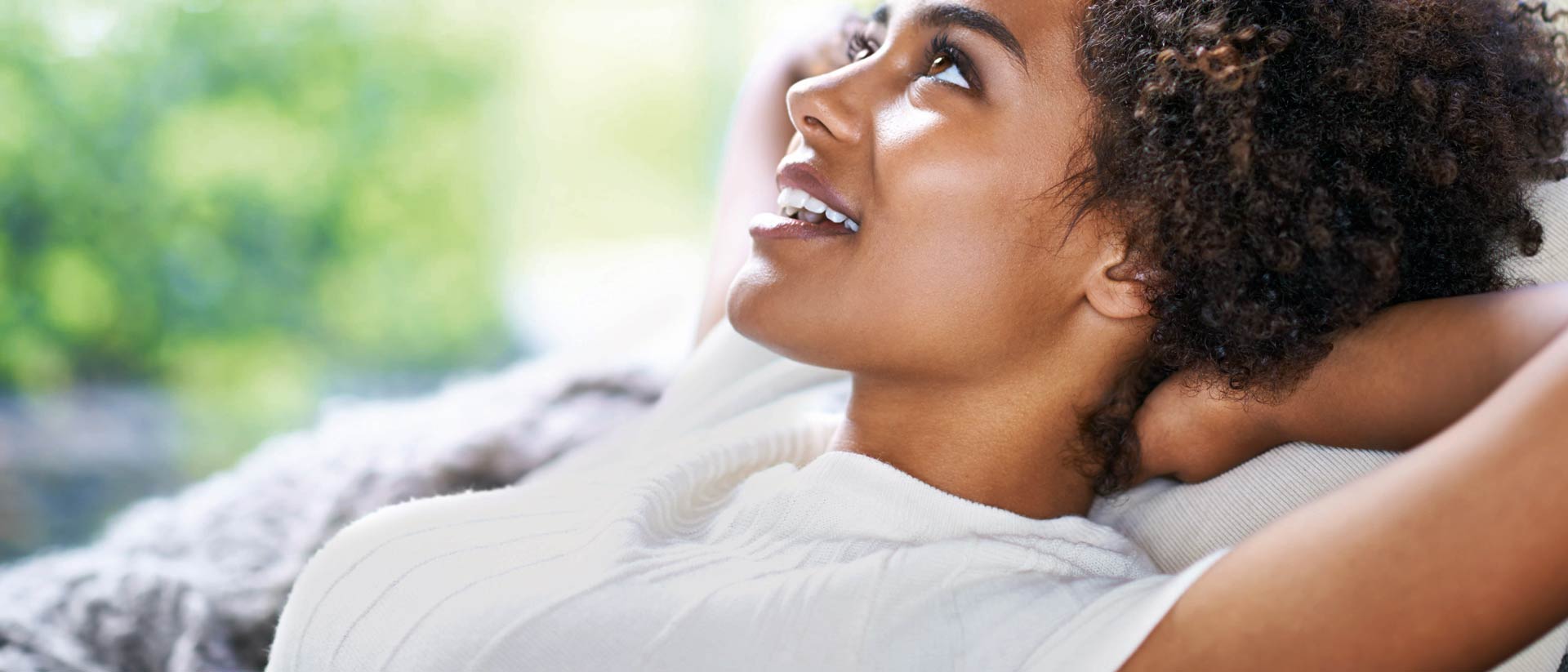 smiling girl leaning against green background, wearing sustainable apparel