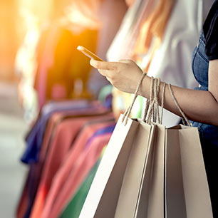 Shopper holding phone and bags