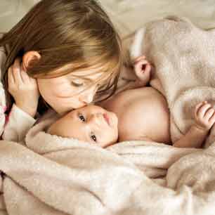 Girl kissing baby in a blanket