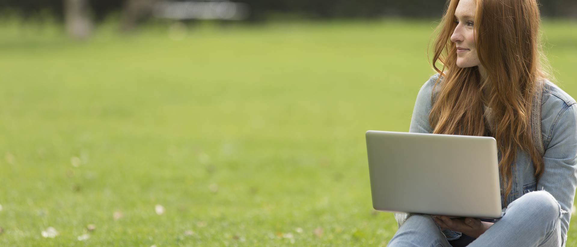 Designer sitting in grass with laptop