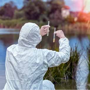 Expert in PPE collecting samples from water near textile factory