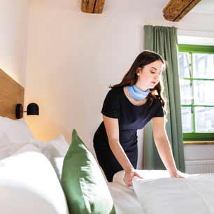 Woman making bed with white sheets