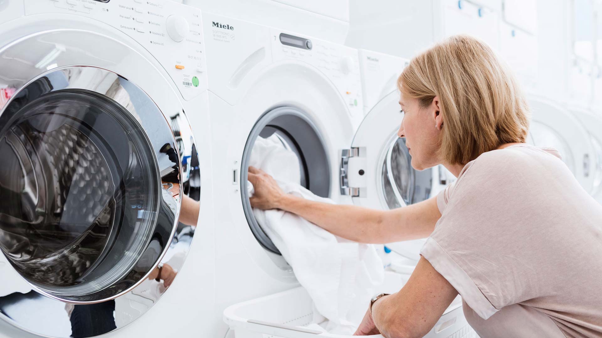 Woman putting towel in a laundry-testing washing machine