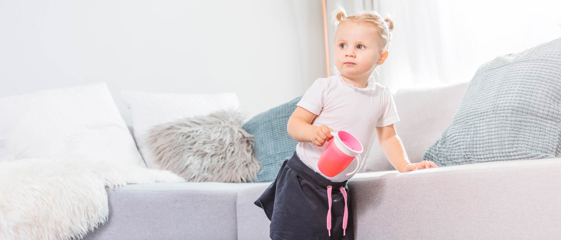 Toddler standing on carpet, leaning on couch