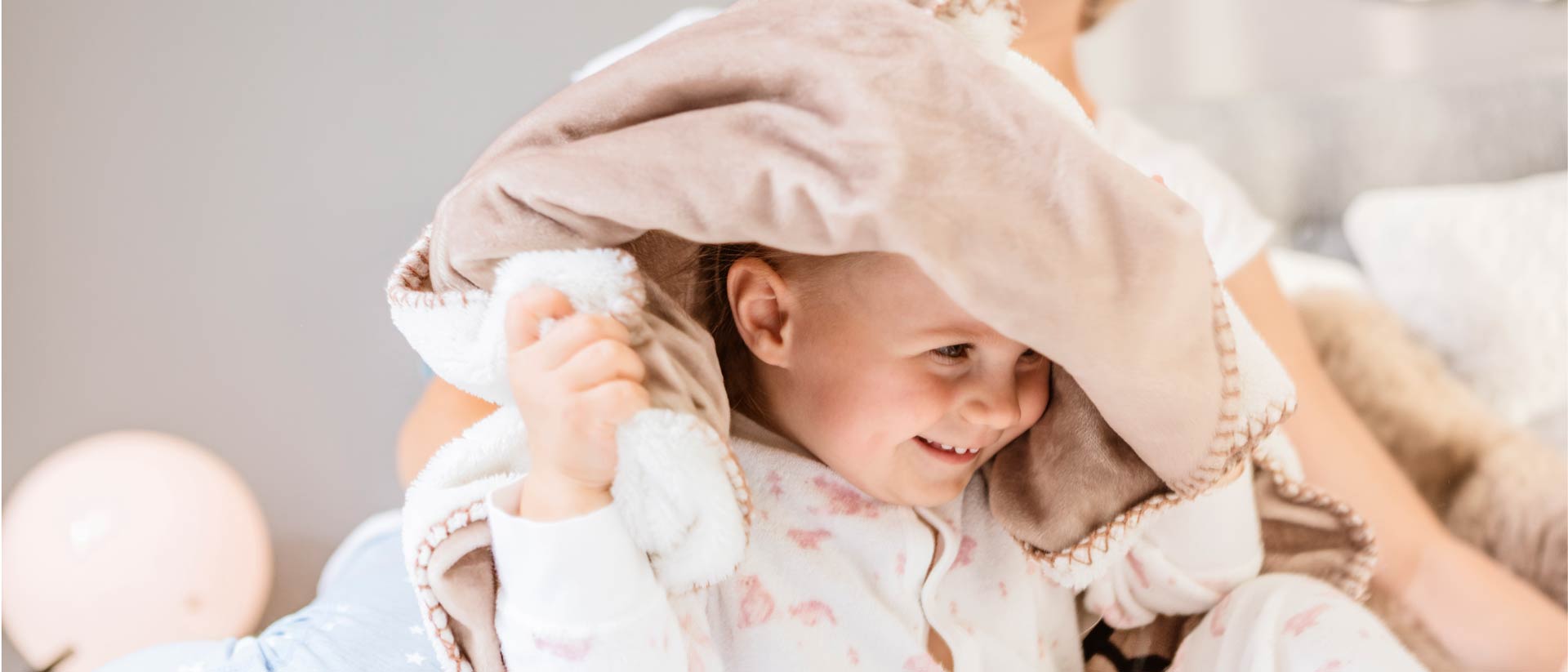 Toddler lifting blanket over her head