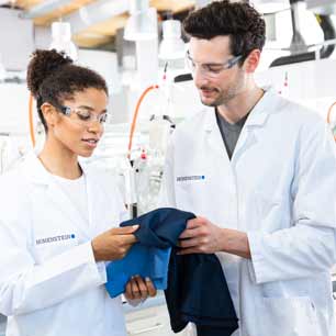 Two Hohenstein laboratory technicians analyzing a blue textile