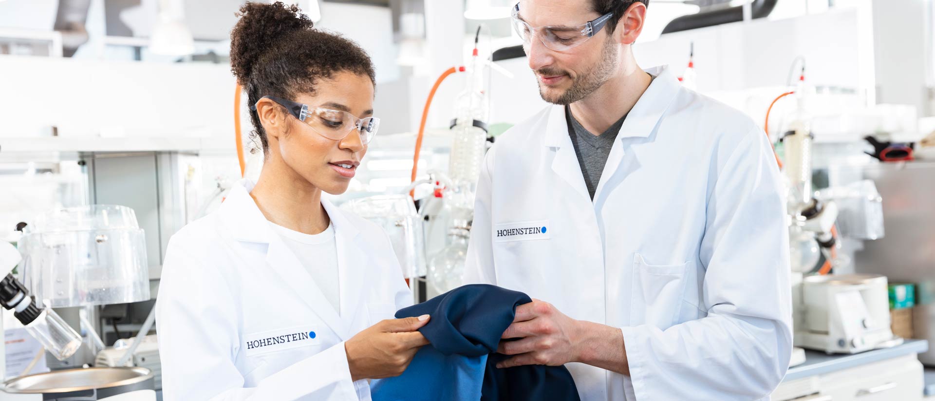 Two Hohenstein lab technicians holding a piece of blue fabric