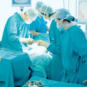 surgeons operating in masks, gowns caps and gloves