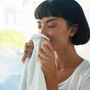 Woman wearing white t-shirt and smelling a white towel