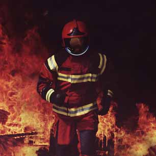 Fire fighter wearing helmet and running out of a fire.