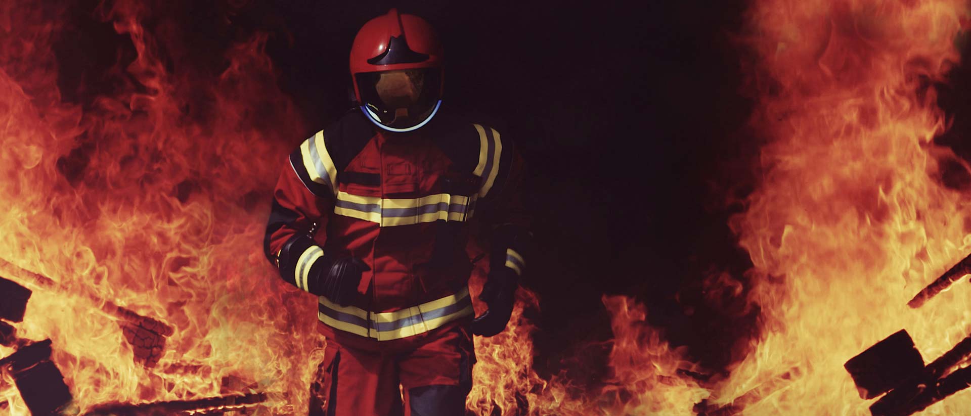 Fire fighter wearing helmet and running out of a fire