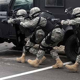 Military personnel wearing ballistic vests in a crouched position