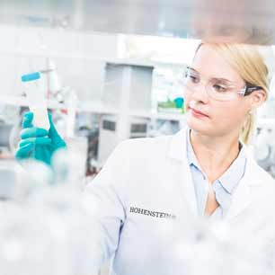 Hohenstein chemist holding a flask of tested textile chemicals